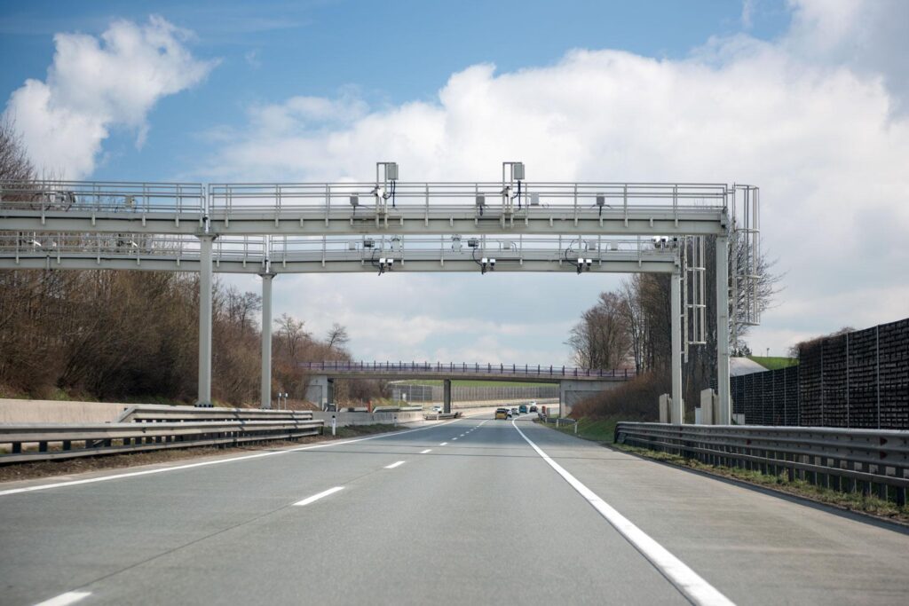 Overhead all-electronic tolling gantry on a highway capturing vehicles with cameras and sensors for cashless toll collection