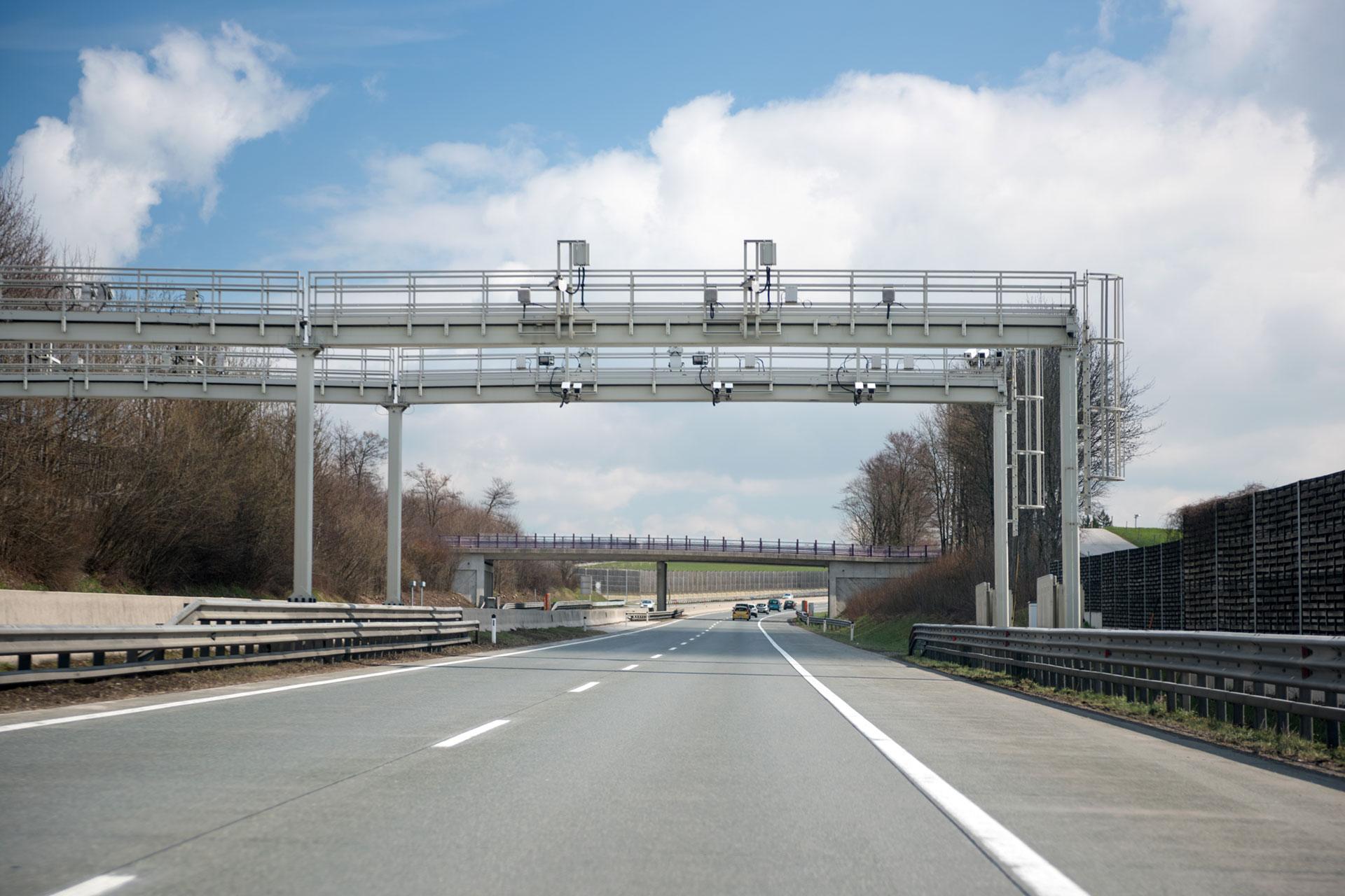 Overhead all-electronic tolling gantry on a highway capturing vehicles with cameras and sensors for cashless toll collection